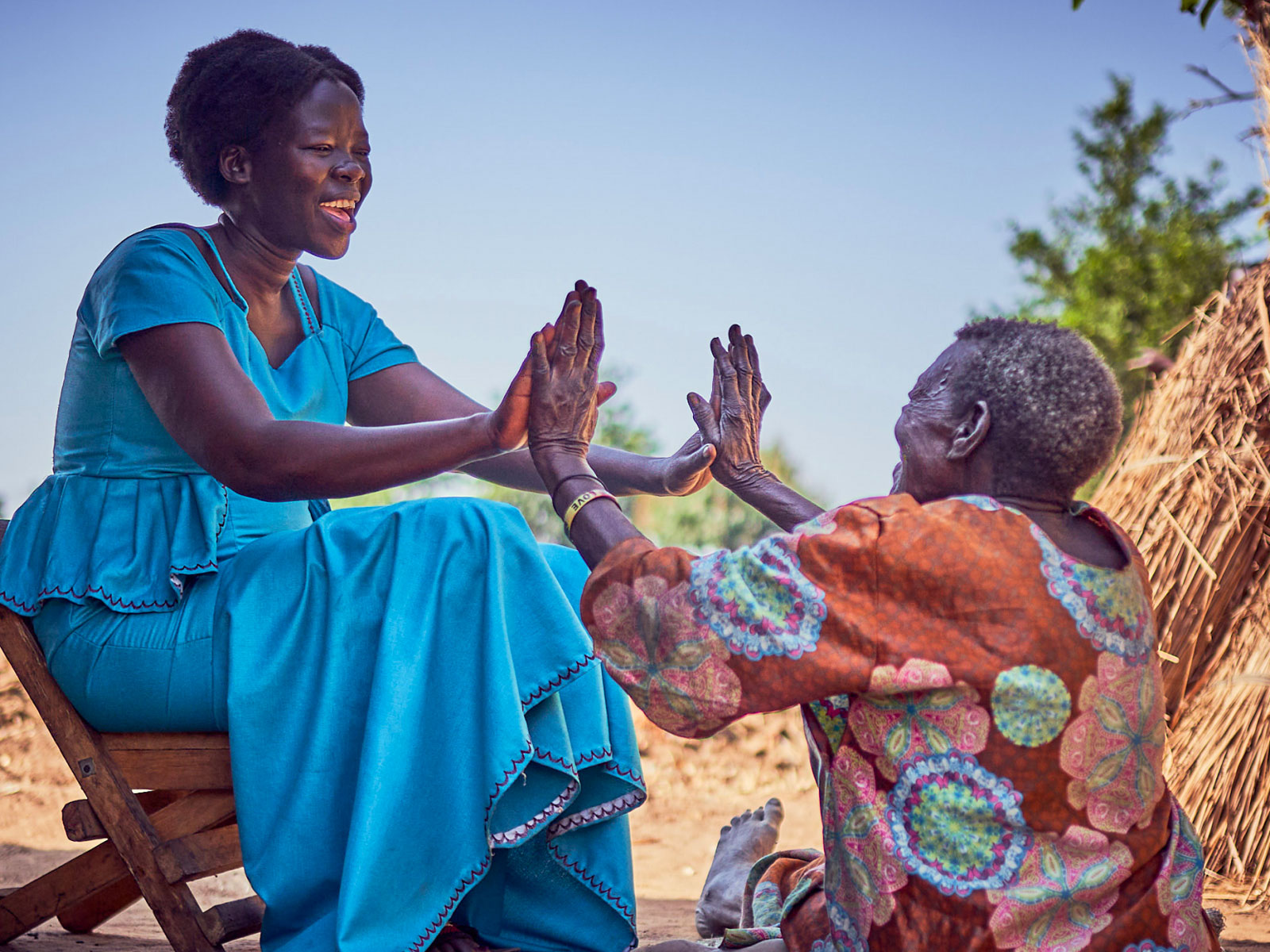 Two women placing both hands against the other woman's hands